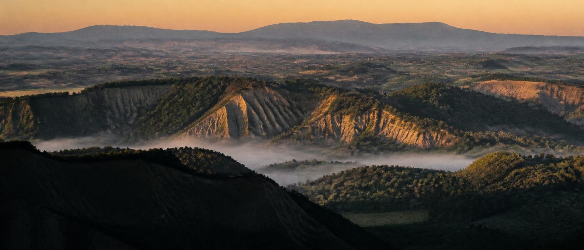 Calanchi e valle della Tuscia al tramonto, con foschia bassa