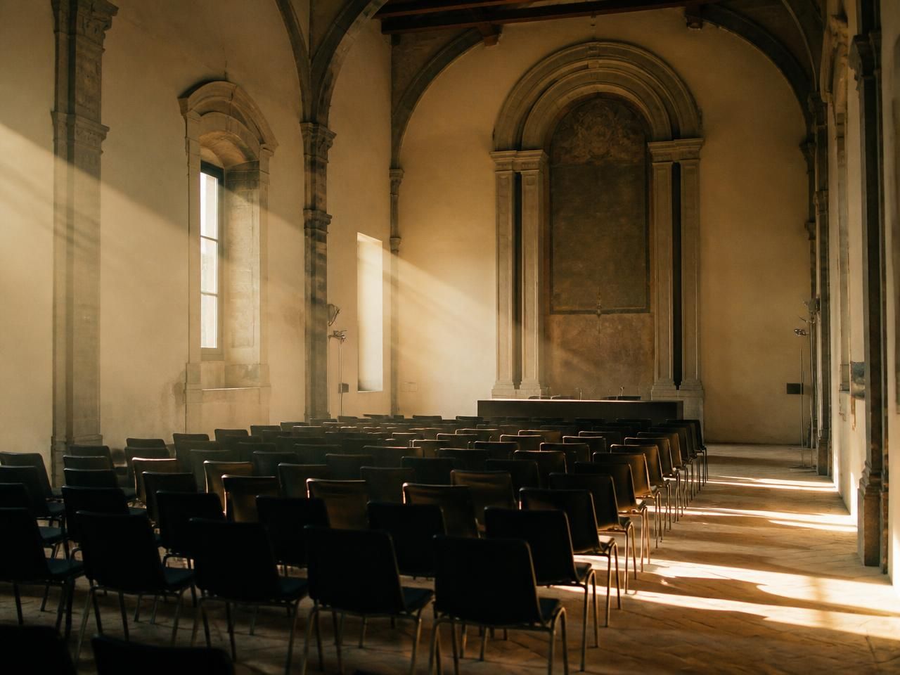 Sala conferenze allestita con sedie in un edificio storico